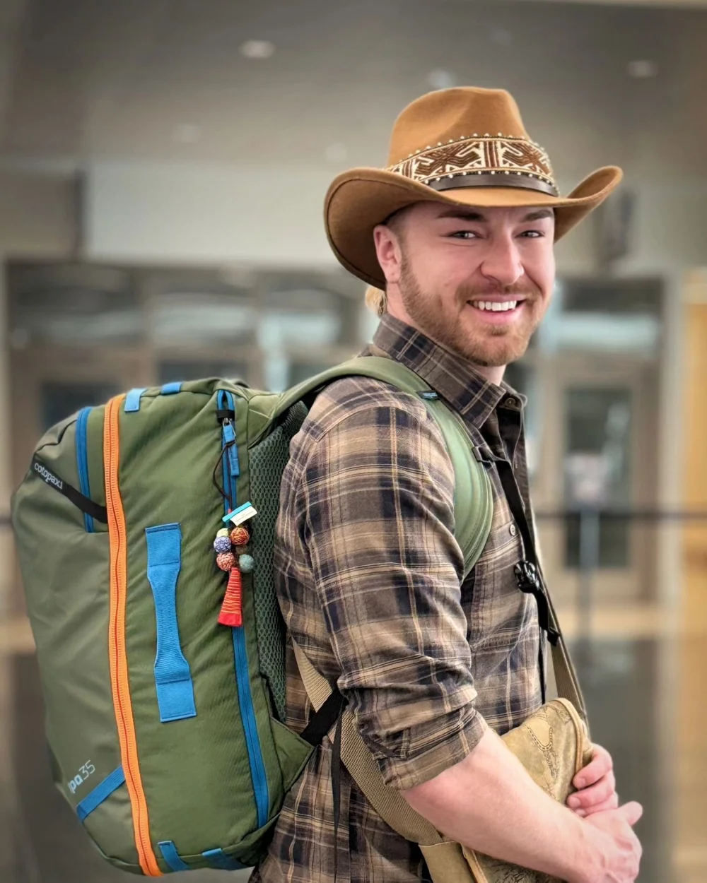 Matt Sheridan in a cowboy hat with a travel backpack at the airport